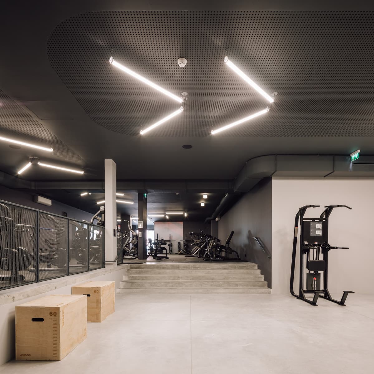Training area with plywood boxes, concrete steps up to the weights zone and zigzag tube lights overhead