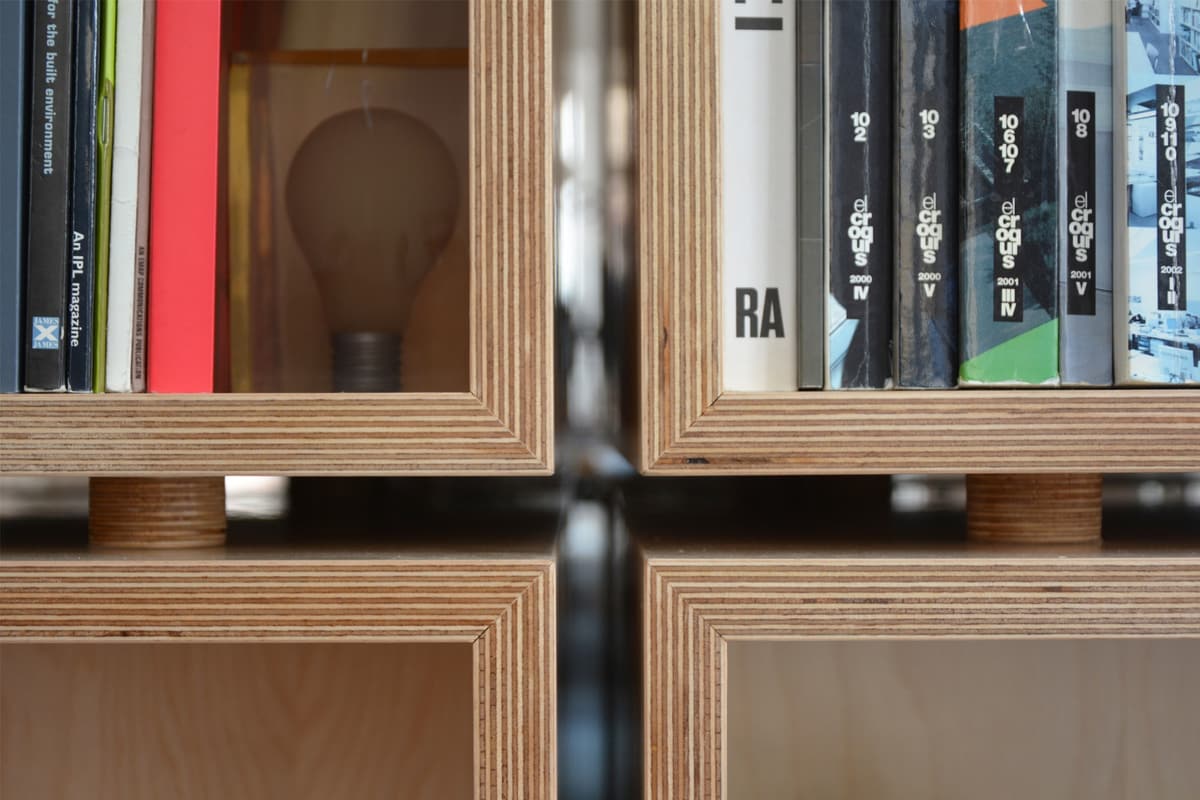 Close-up of plywood shelving units in the NOZ office holding architecture books and magazines