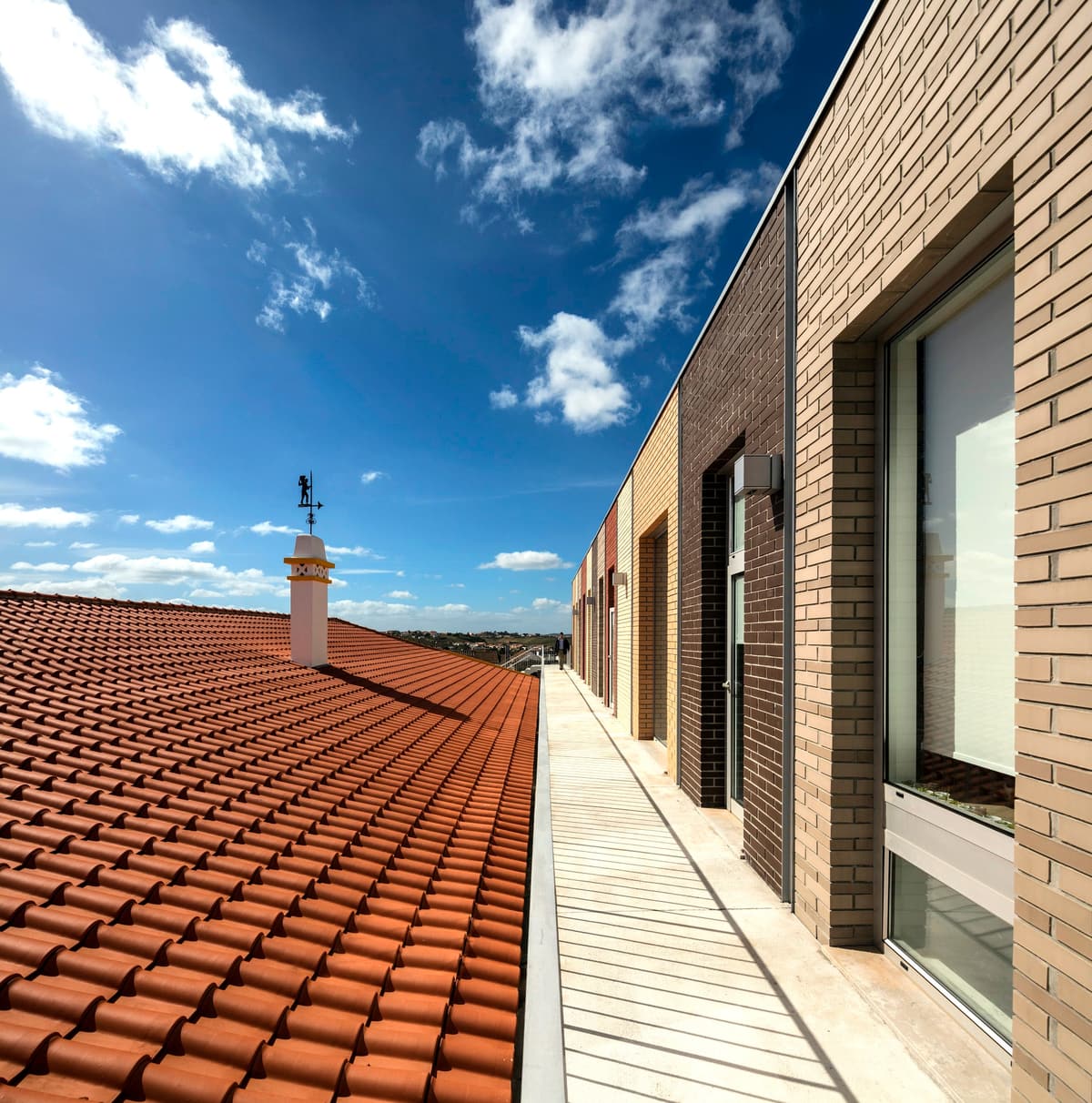 Upper walkway between the clay tile roof of the old school and the multicoloured brick classrooms